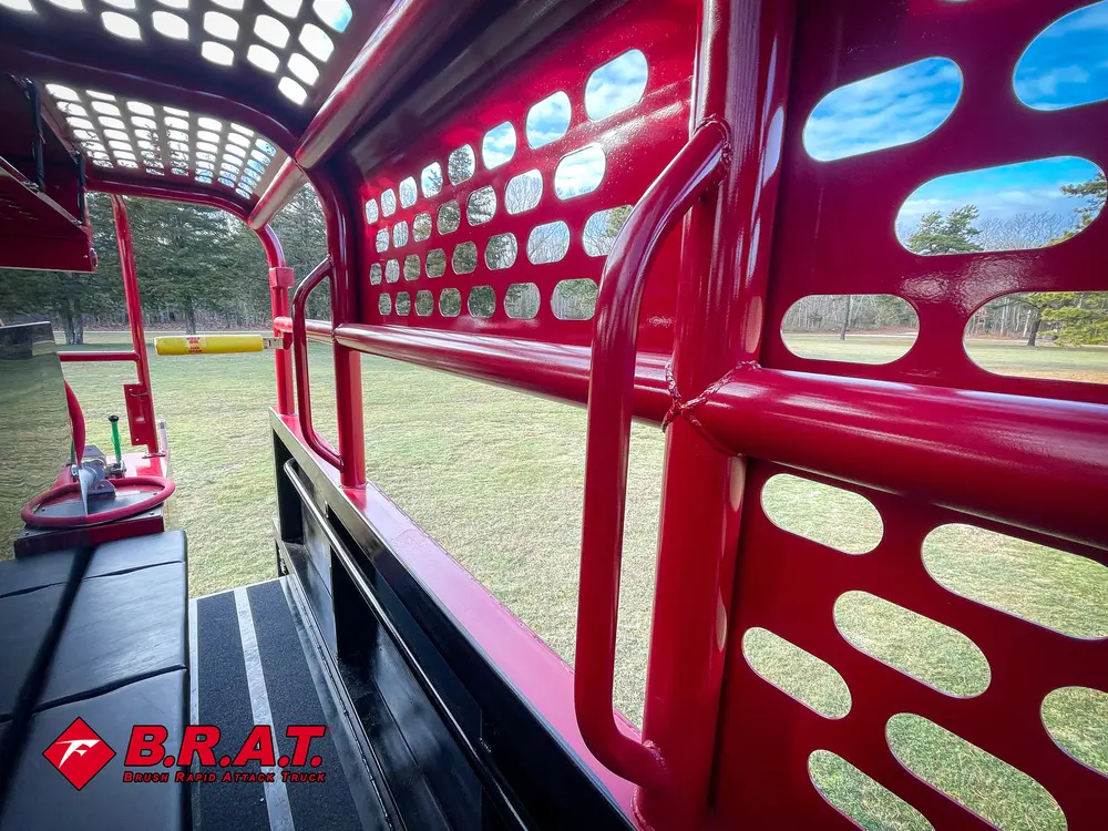 Exterior view of small fire truck showing cab, body compartments, and wheel/tire area.