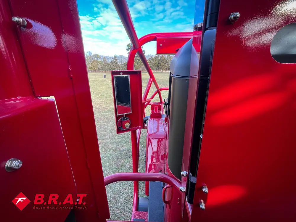 Exterior view of small fire truck showing cab, body compartments, and wheel/tire area.