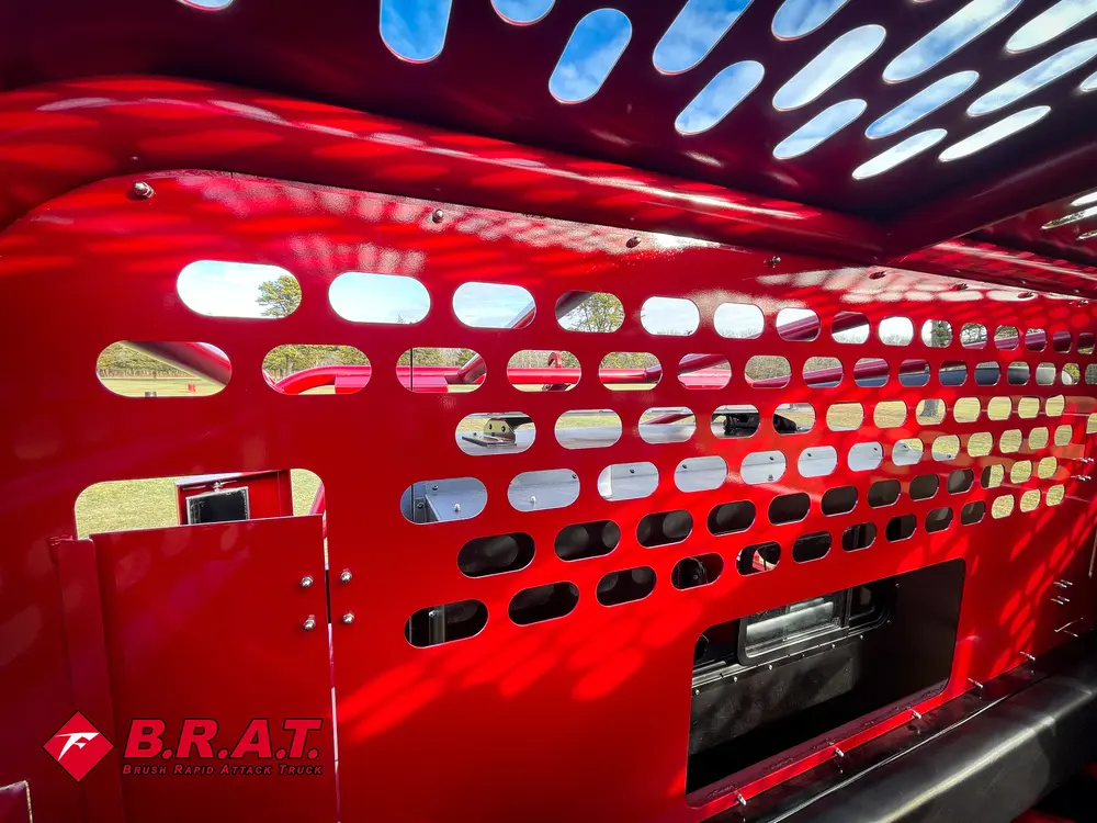 Exterior view of small fire truck showing cab, body compartments, and wheel/tire area.