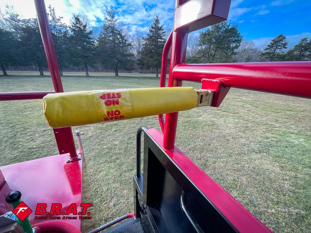 Exterior view of small fire truck showing cab, body compartments, and wheel/tire area.