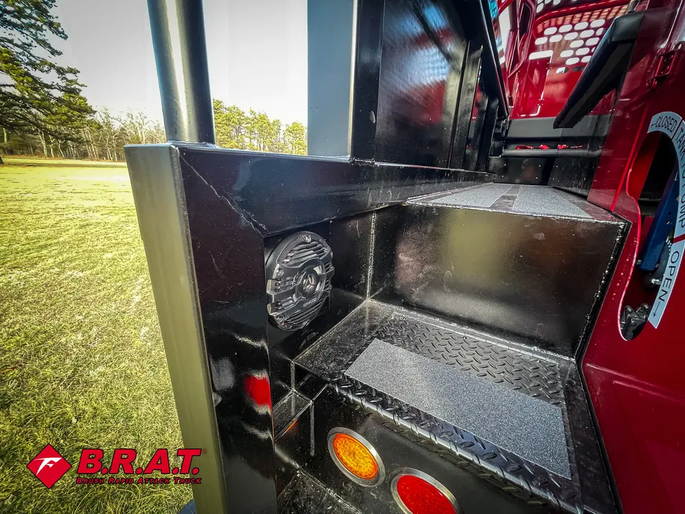 Exterior view of small fire truck showing cab, body compartments, and wheel/tire area.