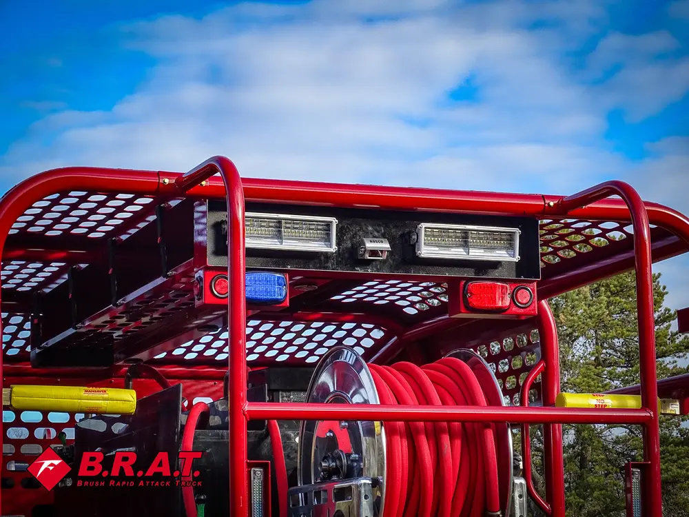 Exterior view of small fire truck showing cab, body compartments, and wheel/tire area.
