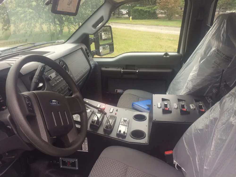 Exterior view of small fire truck showing cab, body compartments, and wheel/tire area.