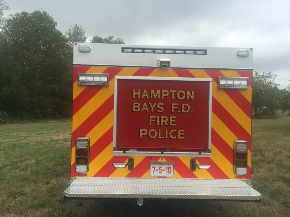 Exterior view of small fire truck showing cab, body compartments, and wheel/tire area.
