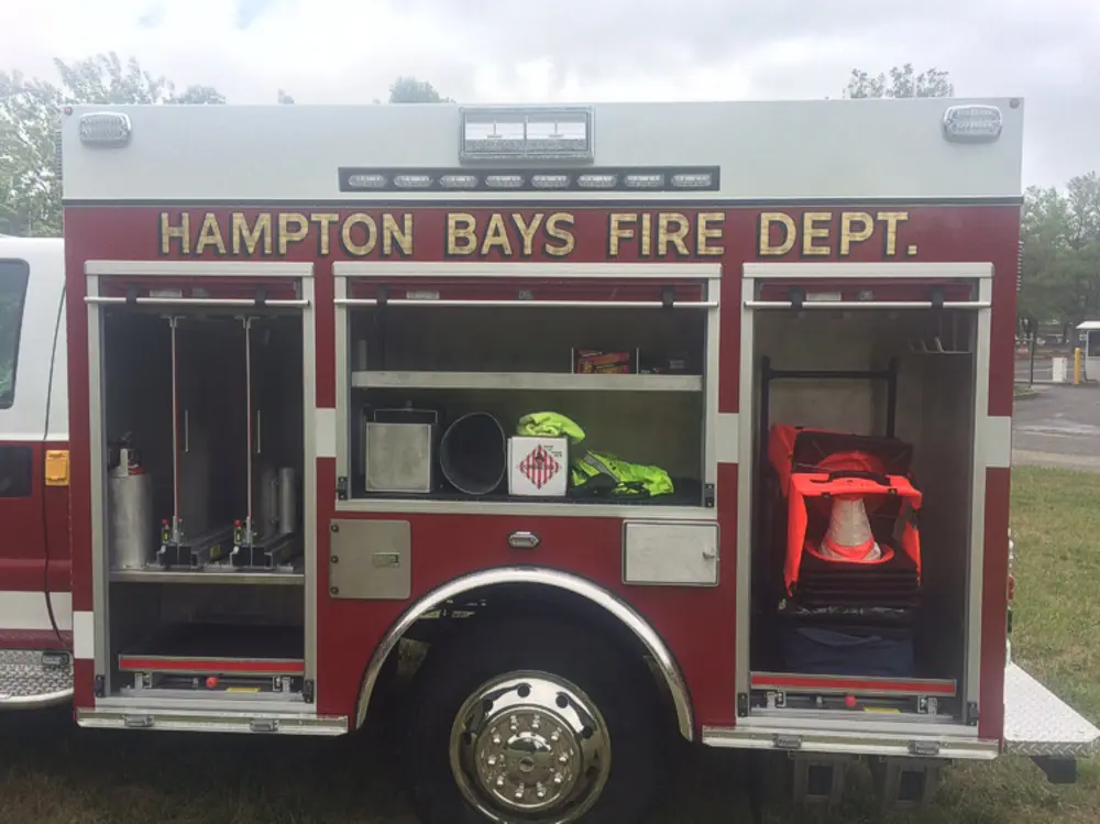 Exterior view of small fire truck showing cab, body compartments, and wheel/tire area.