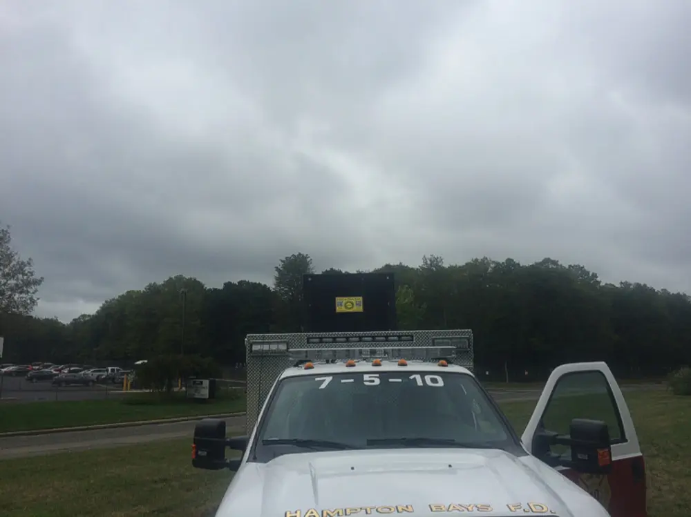 Exterior view of small fire truck showing cab, body compartments, and wheel/tire area.