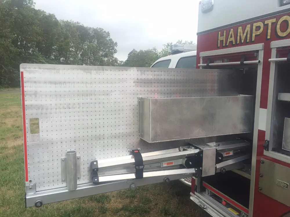 Exterior view of small fire truck showing cab, body compartments, and wheel/tire area.