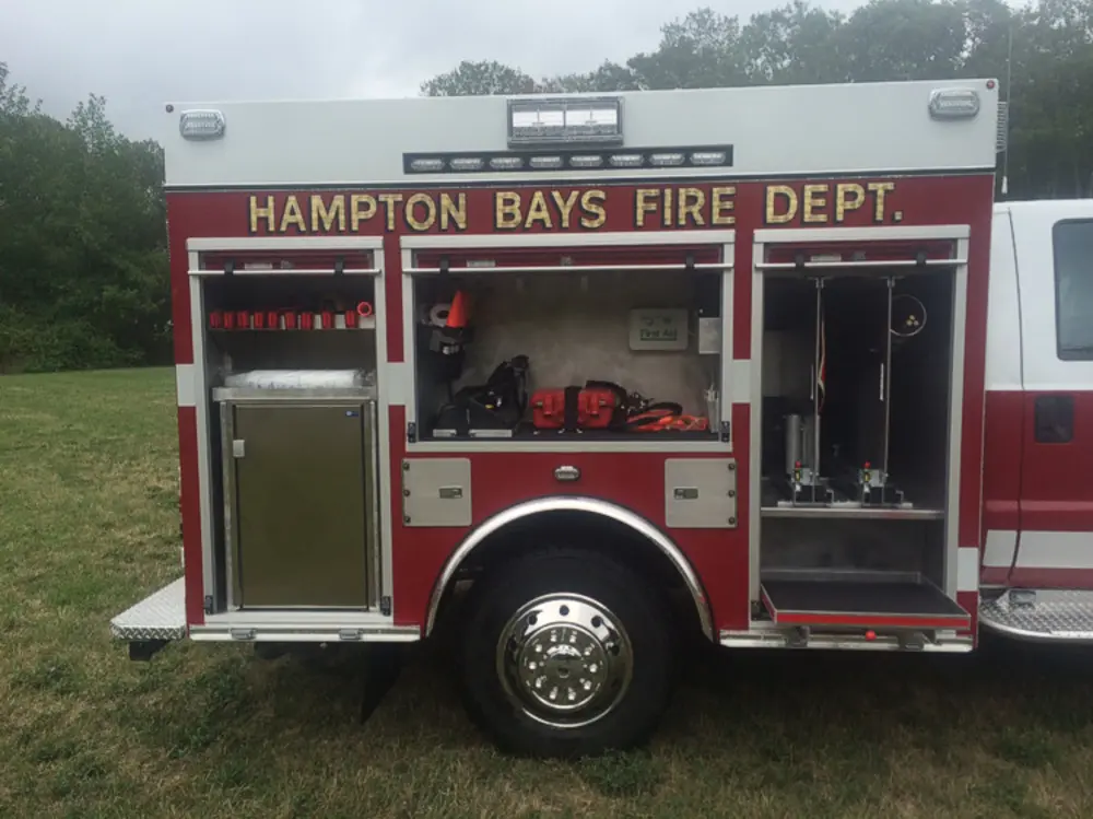 Exterior view of small fire truck showing cab, body compartments, and wheel/tire area.
