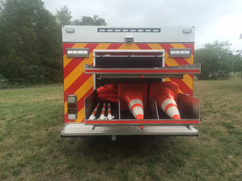 Exterior view of small fire truck showing cab, body compartments, and wheel/tire area.