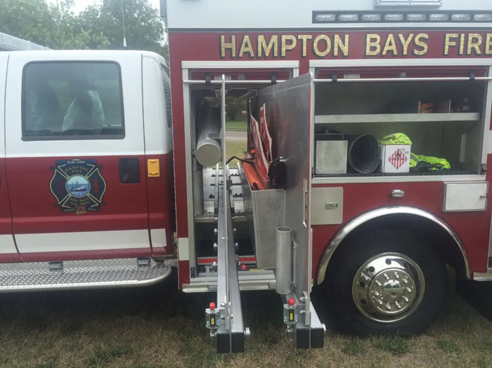 Exterior view of small fire truck showing cab, body compartments, and wheel/tire area.
