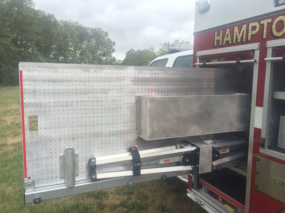 Exterior view of small fire truck showing cab, body compartments, and wheel/tire area.