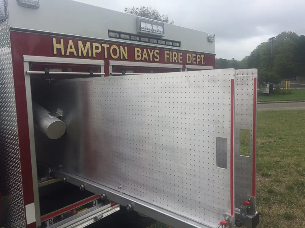 Exterior view of small fire truck showing cab, body compartments, and wheel/tire area.