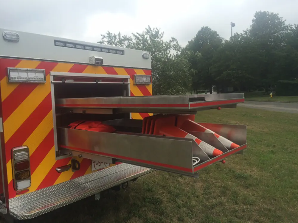 Exterior view of small fire truck showing cab, body compartments, and wheel/tire area.
