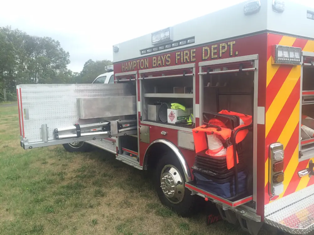 Exterior view of small fire truck showing cab, body compartments, and wheel/tire area.