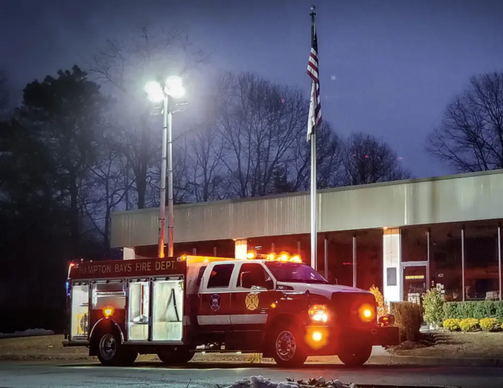 Exterior view of small fire truck showing cab, body compartments, and wheel/tire area.