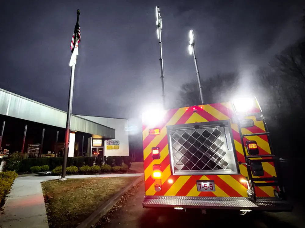 Exterior view of small fire truck showing cab, body compartments, and wheel/tire area.