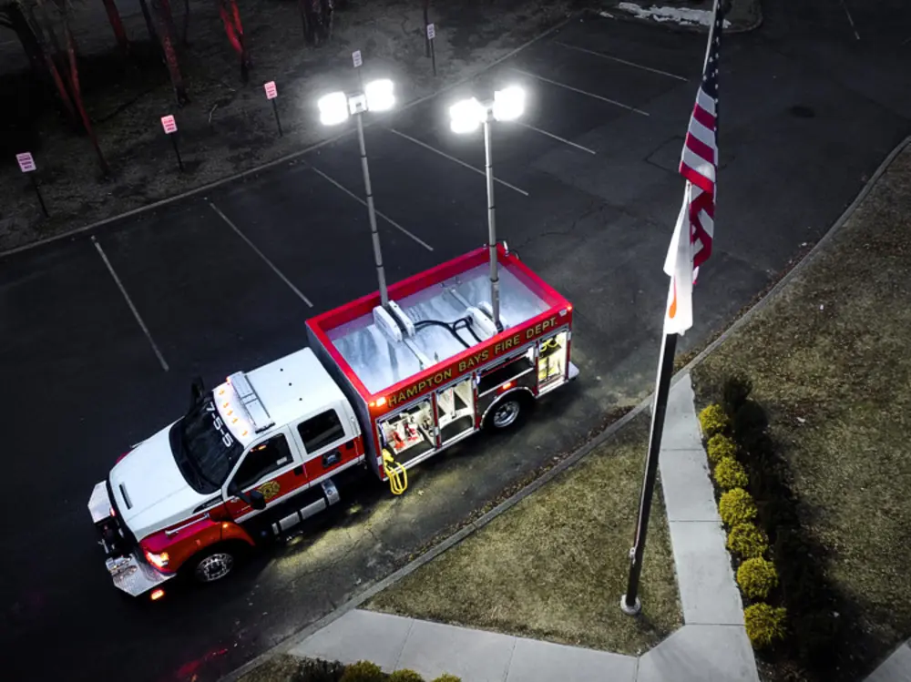 Exterior view of small fire truck showing cab, body compartments, and wheel/tire area.