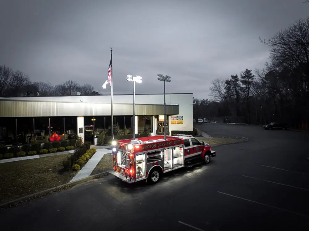 Exterior view of small fire truck showing cab, body compartments, and wheel/tire area.