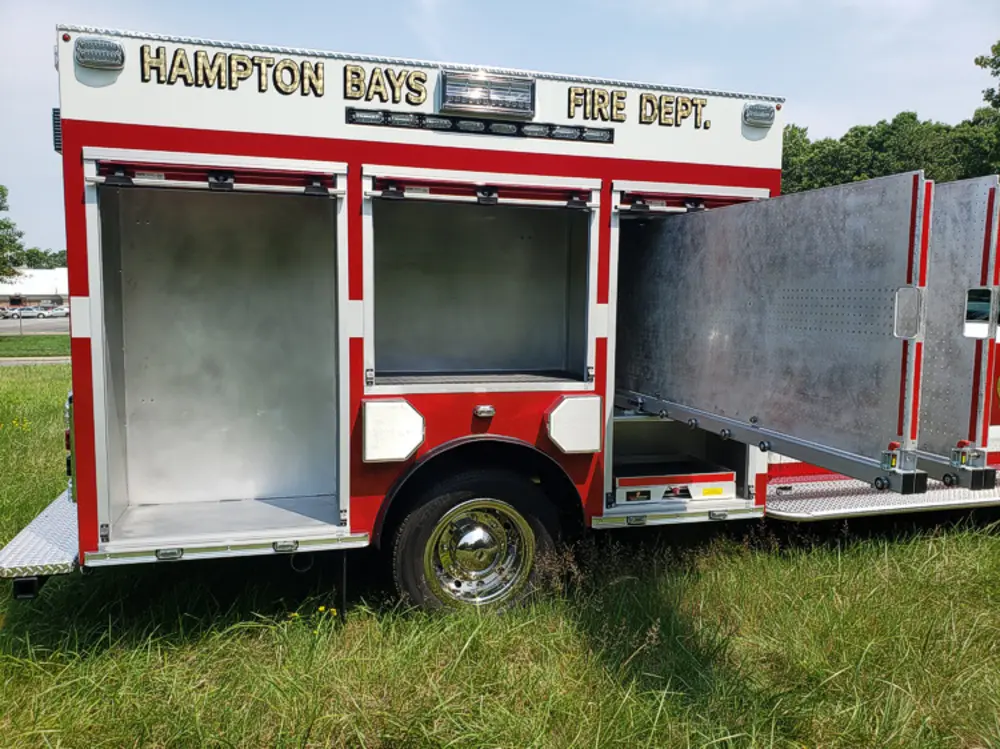 Exterior view of small fire truck showing cab, body compartments, and wheel/tire area.