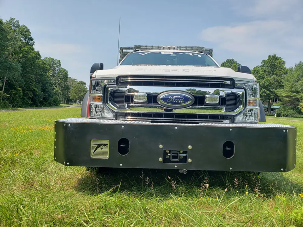 Exterior view of small fire truck showing cab, body compartments, and wheel/tire area.