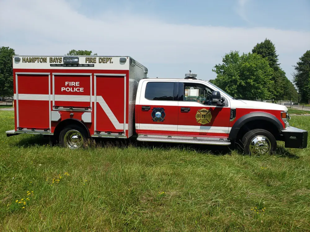 Exterior view of small fire truck showing cab, body compartments, and wheel/tire area.