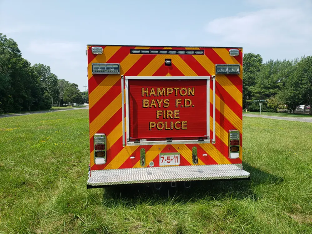 Exterior view of small fire truck showing cab, body compartments, and wheel/tire area.