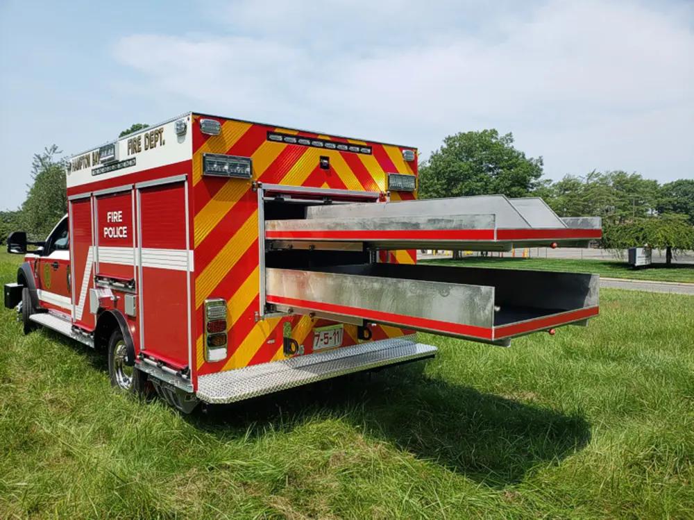 Exterior view of small fire truck showing cab, body compartments, and wheel/tire area.