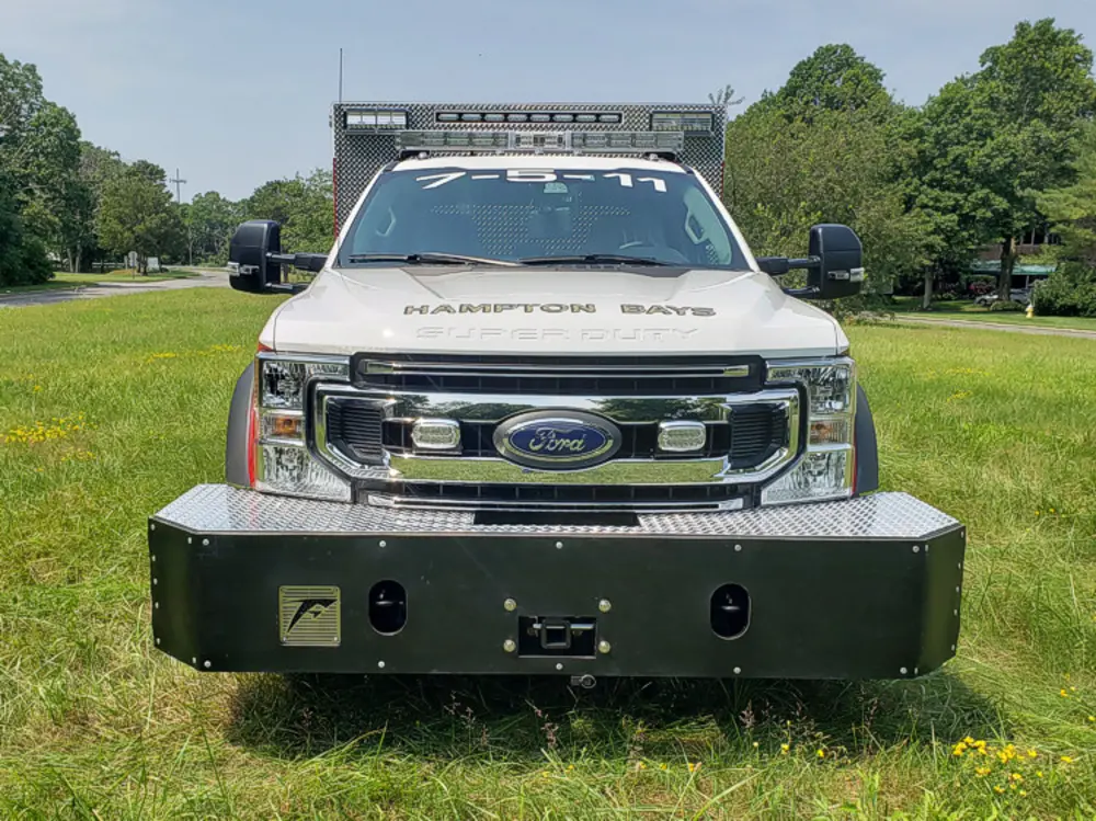 Exterior view of small fire truck showing cab, body compartments, and wheel/tire area.