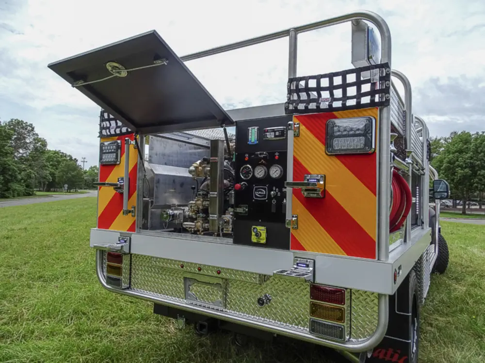 Exterior view of small fire truck showing cab, body compartments, and wheel/tire area.