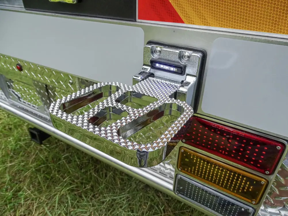 Exterior view of small fire truck showing cab, body compartments, and wheel/tire area.
