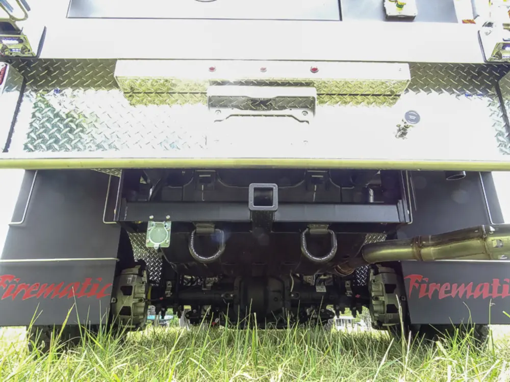 Exterior view of small fire truck showing cab, body compartments, and wheel/tire area.