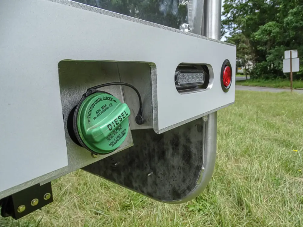 Exterior view of small fire truck showing cab, body compartments, and wheel/tire area.