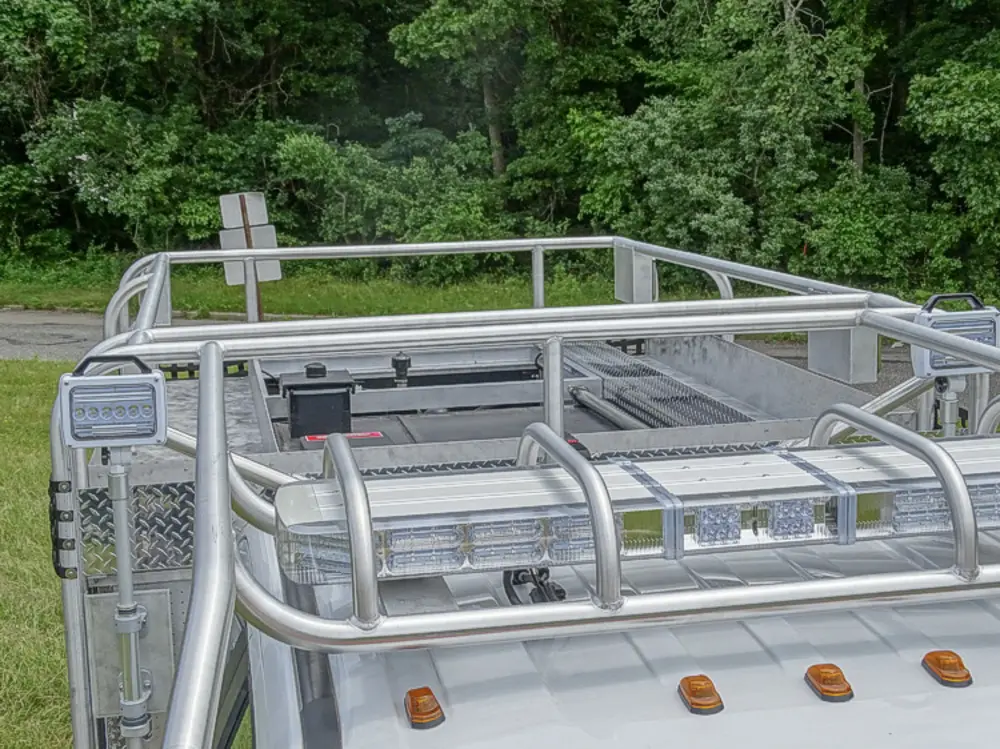 Exterior view of small fire truck showing cab, body compartments, and wheel/tire area.