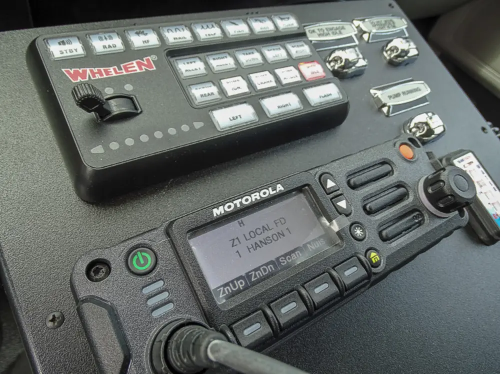 Exterior view of small fire truck showing cab, body compartments, and wheel/tire area.