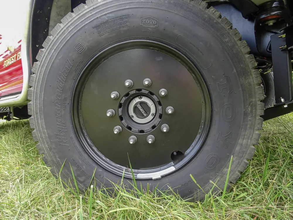 Exterior view of small fire truck showing cab, body compartments, and wheel/tire area.