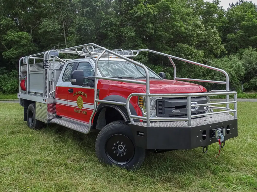 Exterior view of small fire truck showing cab, body compartments, and wheel/tire area.