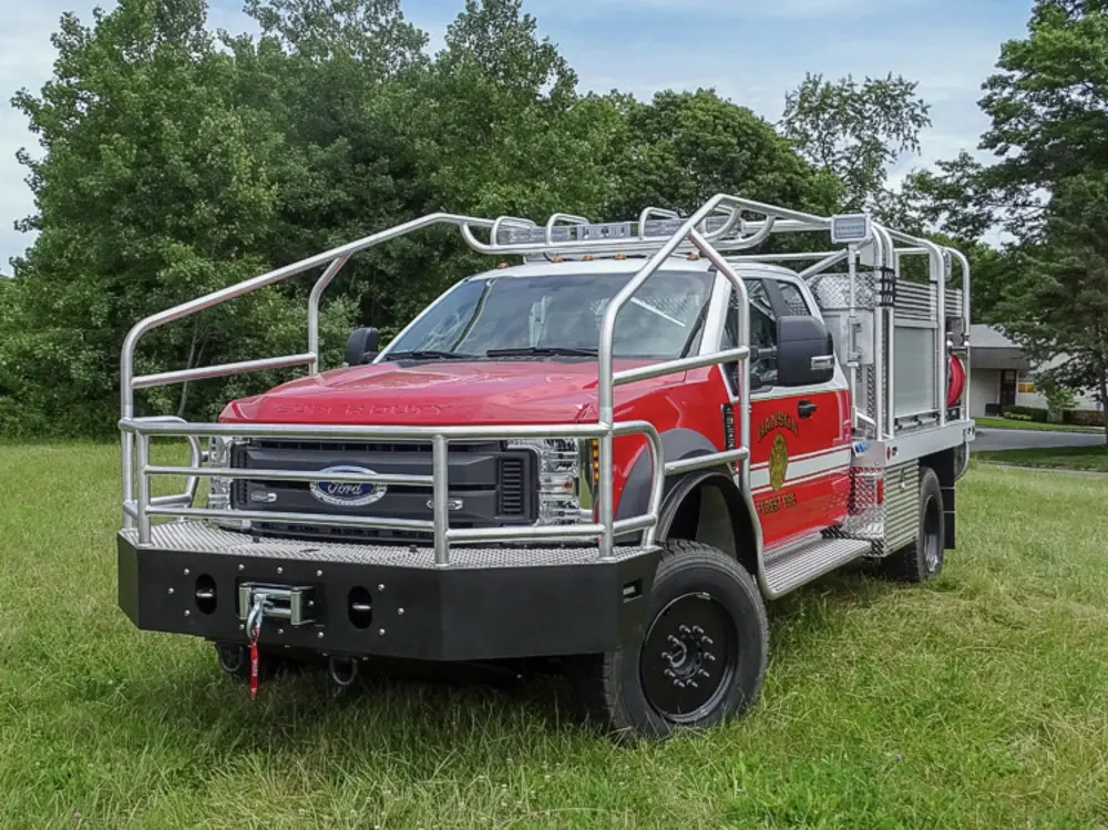 Exterior view of small fire truck showing cab, body compartments, and wheel/tire area.