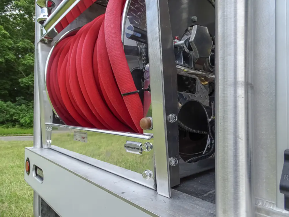Exterior view of small fire truck showing cab, body compartments, and wheel/tire area.