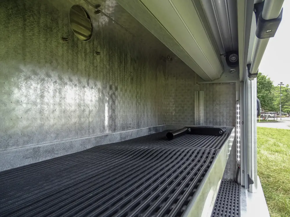 Exterior view of small fire truck showing cab, body compartments, and wheel/tire area.