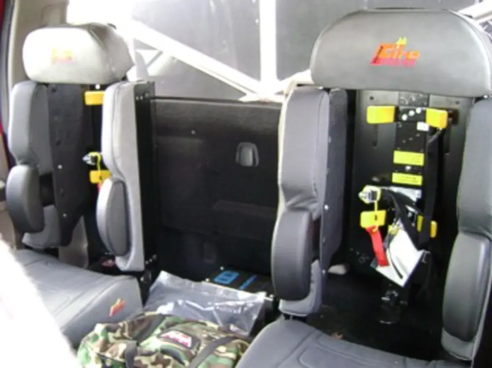 Exterior view of small fire truck showing cab, body compartments, and wheel/tire area.