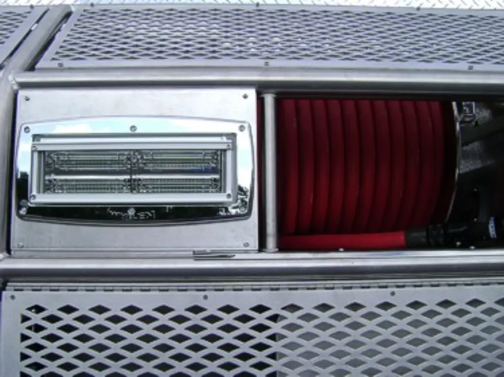 Exterior view of small fire truck showing cab, body compartments, and wheel/tire area.