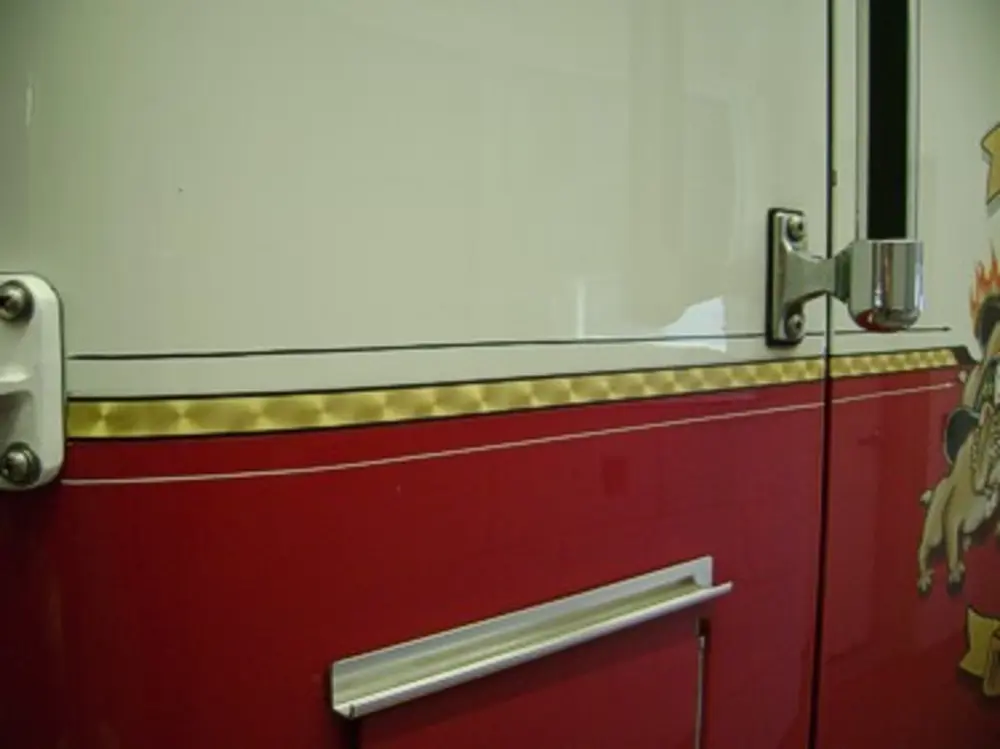 Exterior view of small fire truck showing cab, body compartments, and wheel/tire area.