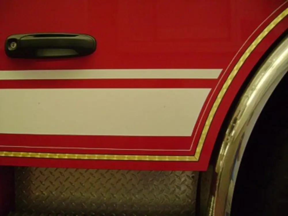 Exterior view of small fire truck showing cab, body compartments, and wheel/tire area.