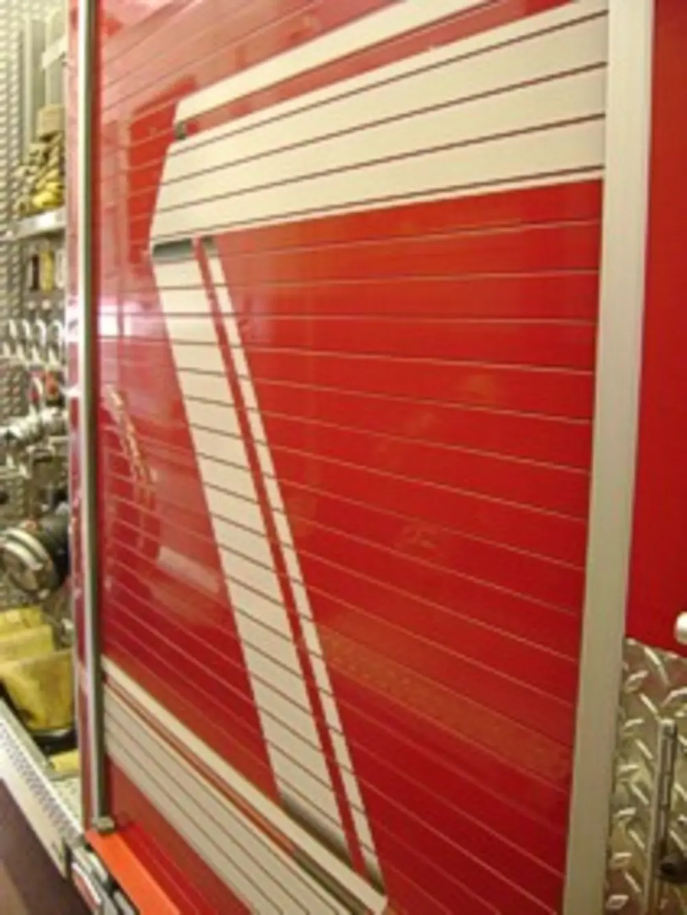 Exterior view of small fire truck showing cab, body compartments, and wheel/tire area.