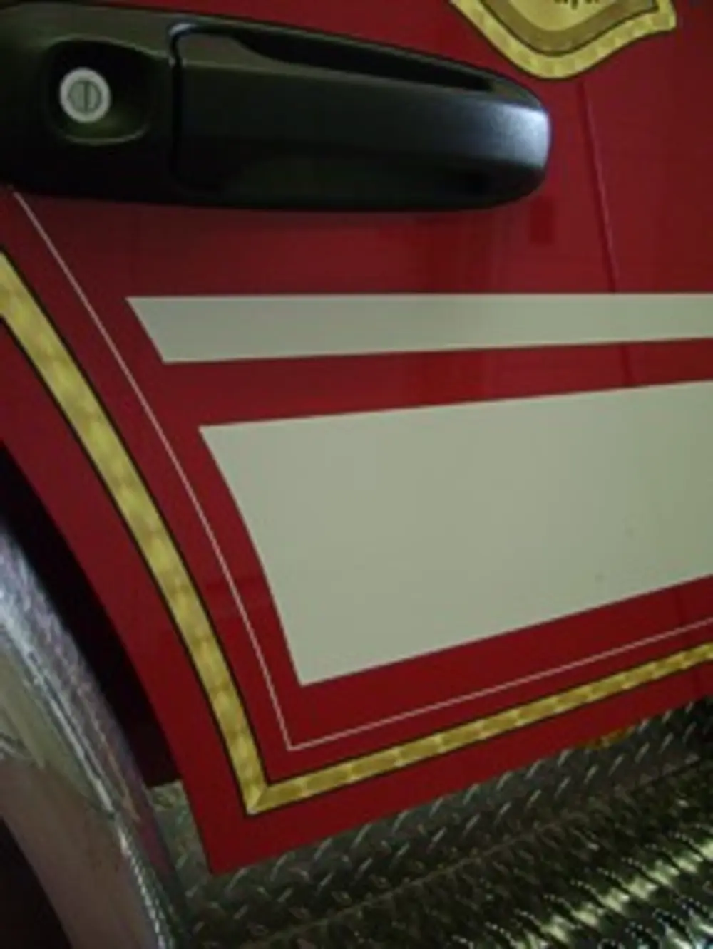 Exterior view of small fire truck showing cab, body compartments, and wheel/tire area.