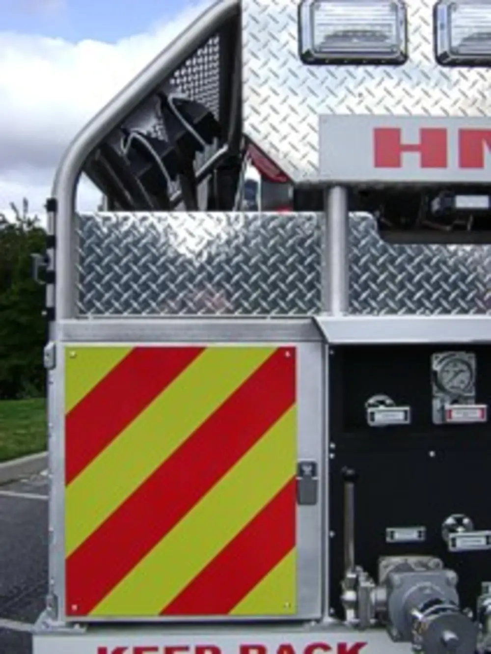 Exterior view of small fire truck showing cab, body compartments, and wheel/tire area.