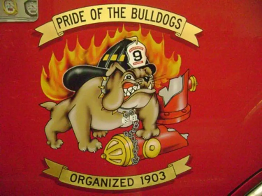 Exterior view of small fire truck showing cab, body compartments, and wheel/tire area.