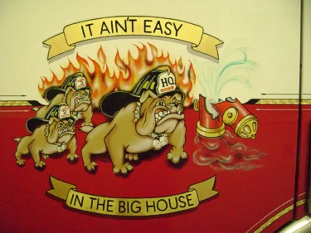 Exterior view of small fire truck showing cab, body compartments, and wheel/tire area.