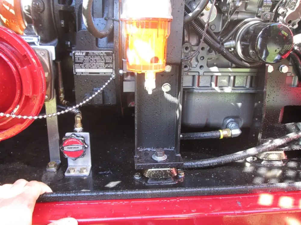 Exterior view of small fire truck showing cab, body compartments, and wheel/tire area.