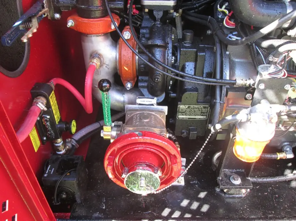 Exterior view of small fire truck showing cab, body compartments, and wheel/tire area.